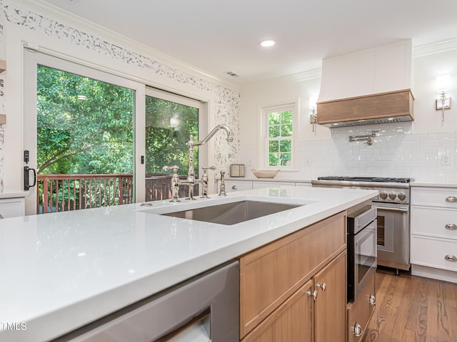 3009 Hillmer Dr, Raleigh, NC 27609 - kitchen with ornamental molding, light wood finished floors, stainless steel stove, a sink, and light countertops