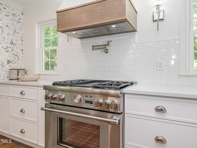 3009 Hillmer Dr, Raleigh, NC 27609 - kitchen with custom exhaust hood, decorative backsplash, light countertops, and stainless steel range
