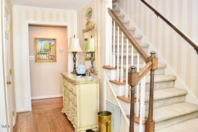 775 Sid Eaves Rd, Youngsville, NC 27596 - stairs featuring wallpapered walls, wood finished floors, visible vents, crown molding, and baseboards