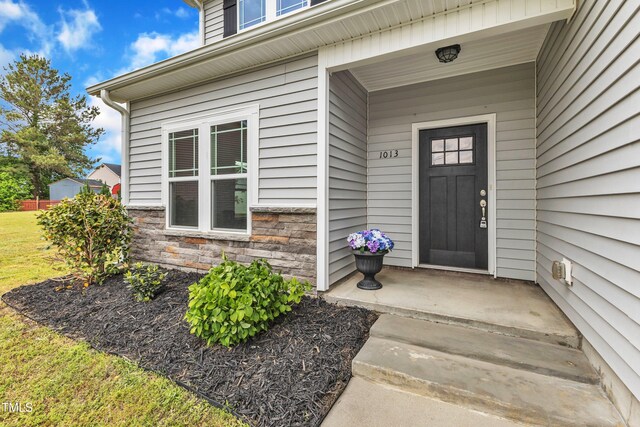 view of exterior entry with covered porch and stone siding