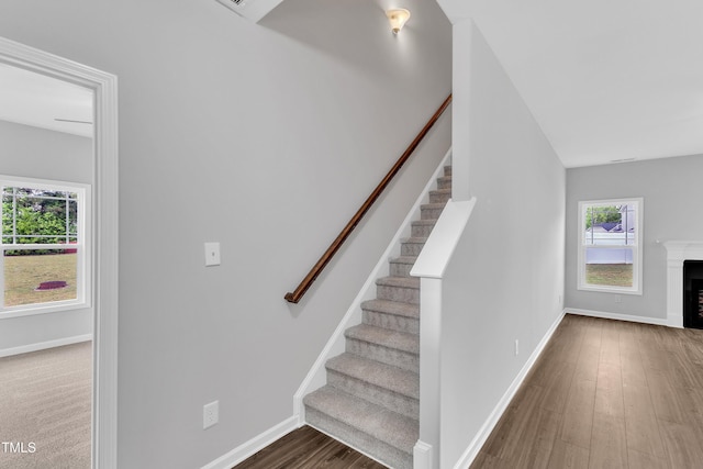 stairway featuring baseboards, wood finished floors, and a fireplace