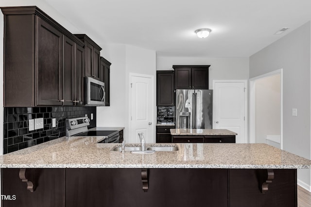 kitchen featuring a sink, appliances with stainless steel finishes, a peninsula, and tasteful backsplash