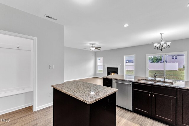 kitchen with stainless steel dishwasher, visible vents, a center island, a sink, and light wood-style flooring