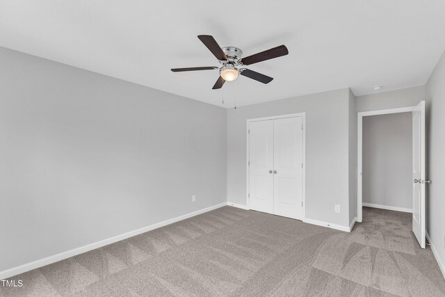 unfurnished bedroom featuring carpet floors, baseboards, a closet, and ceiling fan