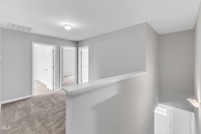hall with visible vents, carpet flooring, and baseboards