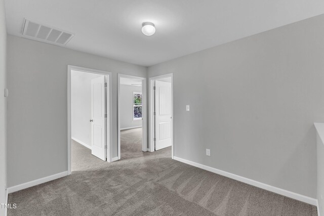 unfurnished bedroom featuring carpet floors, baseboards, and visible vents