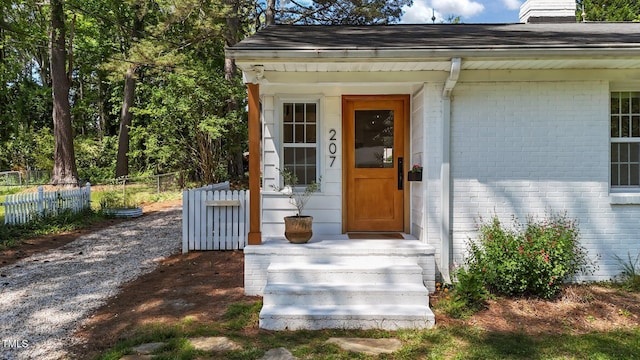 207 N Aiken St, Fuquay Varina, NC 27526 - view of exterior entry with brick siding, fence, and roof with shingles