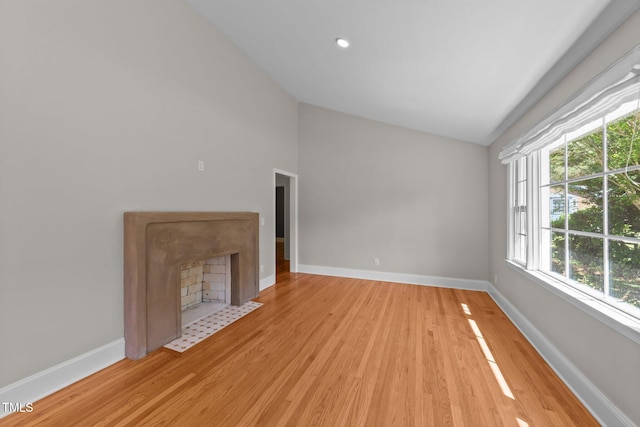 207 N Aiken St, Fuquay Varina, NC 27526 - unfurnished living room with baseboards, a fireplace with flush hearth, wood finished floors, and high vaulted ceiling