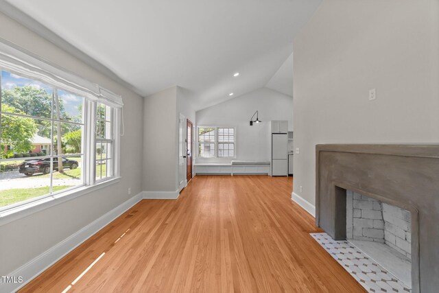 207 N Aiken St, Fuquay Varina, NC 27526 - unfurnished living room with a fireplace with flush hearth, baseboards, vaulted ceiling, and light wood-style flooring