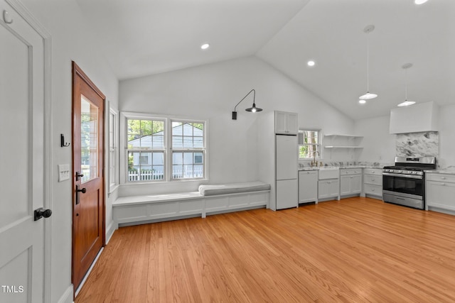 207 N Aiken St, Fuquay Varina, NC 27526 - kitchen featuring white dishwasher, light wood finished floors, stainless steel range with gas stovetop, built in fridge, and lofted ceiling