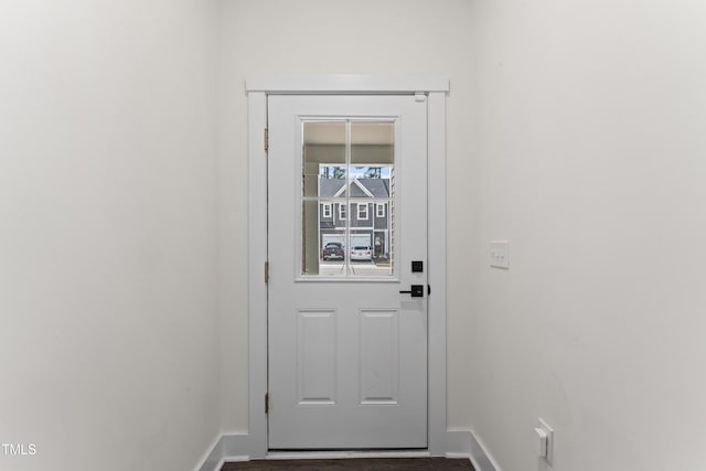 doorway featuring baseboards and dark wood finished floors