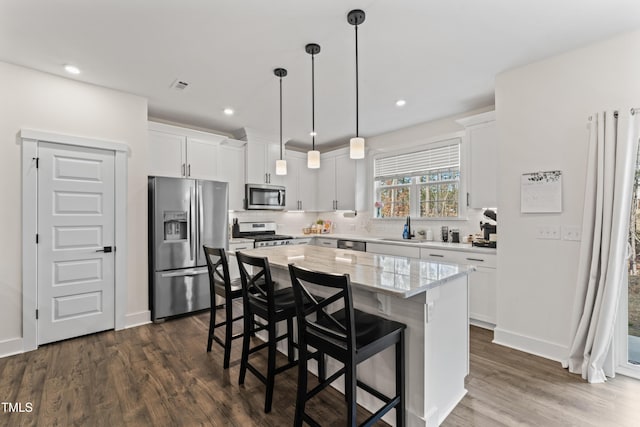 kitchen featuring stainless steel appliances, a breakfast bar, decorative backsplash, white cabinets, and recessed lighting