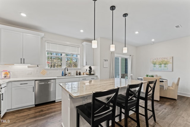 kitchen with stainless steel dishwasher, a sink, decorative backsplash, dark wood-type flooring, and white cabinets