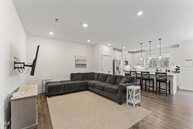 living room with dark wood-type flooring, recessed lighting, and baseboards