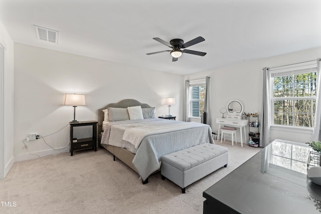 bedroom featuring light carpet, multiple windows, baseboards, and ceiling fan