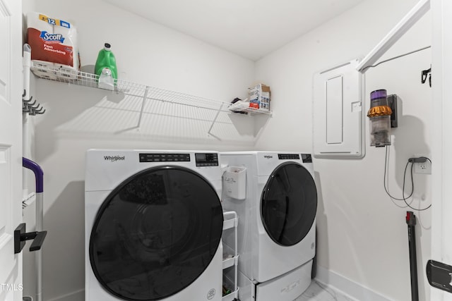 clothes washing area featuring washing machine and dryer, light marble finish flooring, electric panel, and baseboards