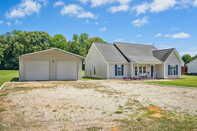 view of front of property featuring a garage, an outbuilding, a front lawn, and a shingled roof