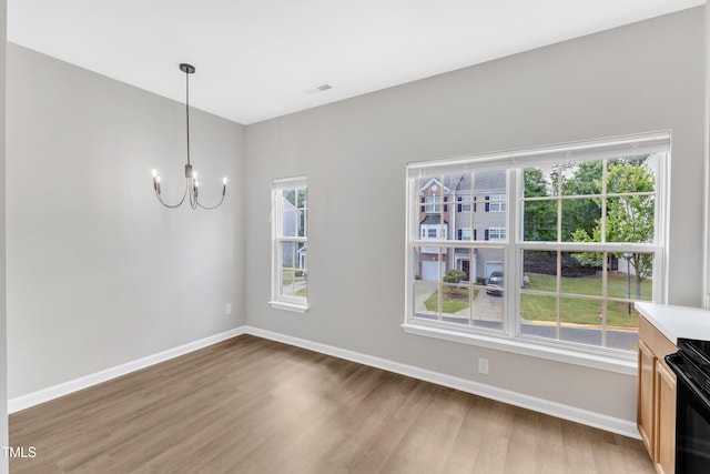 2705 Wyntercrest Ln, Durham, NC 27713 - unfurnished living room with baseboards, an inviting chandelier, a healthy amount of sunlight, and light wood finished floors