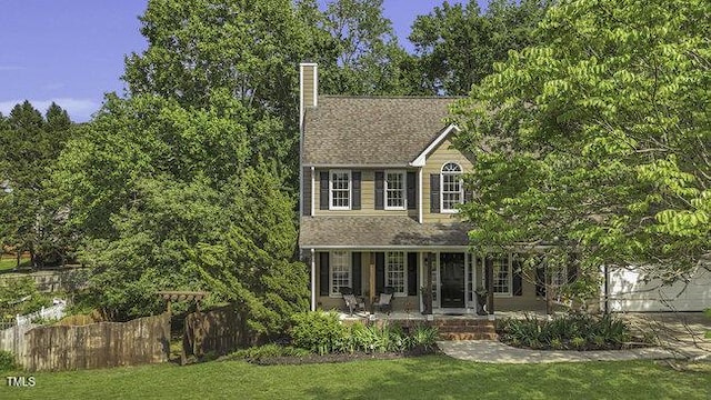 view of front of house featuring fence, a chimney, a porch, and a front yard