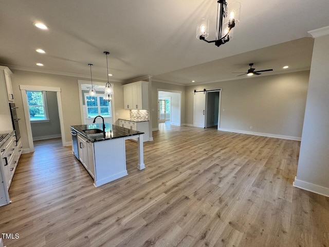 27 Batten Hill Ln, Selma, NC 27576 - kitchen with crown molding, a barn door, recessed lighting, white cabinetry, and an island with sink
