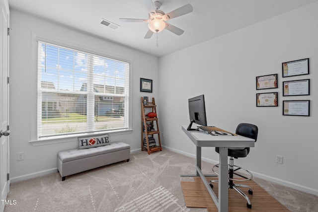 home office with a ceiling fan, baseboards, visible vents, and light carpet