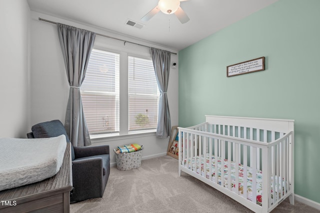 carpeted bedroom with visible vents, baseboards, a nursery area, and multiple windows
