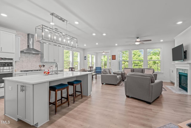 kitchen with wall chimney range hood, gas cooktop, ceiling fan, and recessed lighting