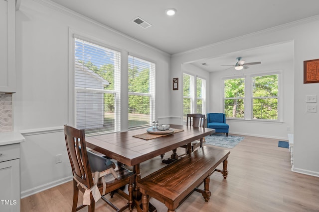 dining room featuring a ceiling fan, visible vents, baseboards, light wood finished floors, and ornamental molding
