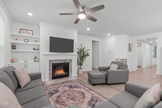 living area featuring a ceiling fan, recessed lighting, a tiled fireplace, and light wood-style flooring