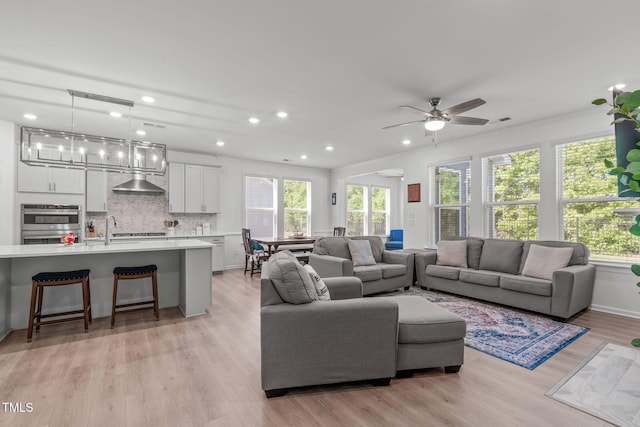 living room featuring a ceiling fan, recessed lighting, and light wood-style flooring