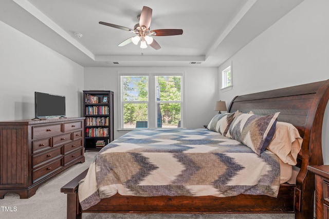 bedroom with ceiling fan, visible vents, light carpet, and a raised ceiling