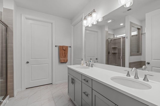 full bathroom featuring visible vents, a sink, marble finish floor, and a shower stall