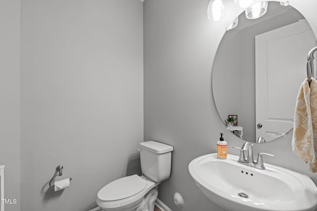 half bathroom featuring baseboards, a sink, and toilet