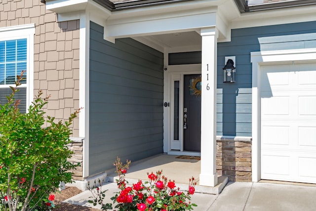 doorway to property featuring a garage and a porch