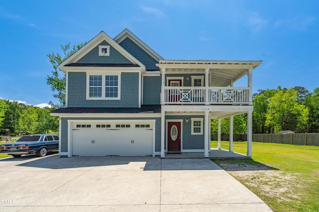 view of front facade featuring fence, an attached garage, a front yard, a balcony, and driveway