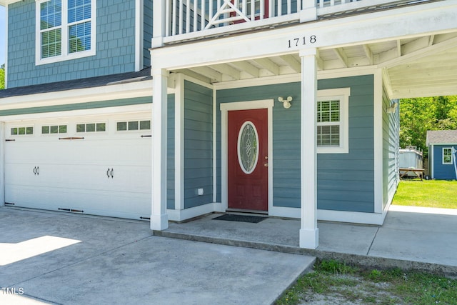 entrance to property featuring a garage, a balcony, and concrete driveway