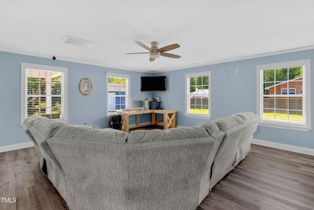 living room with visible vents, crown molding, wood finished floors, baseboards, and a ceiling fan