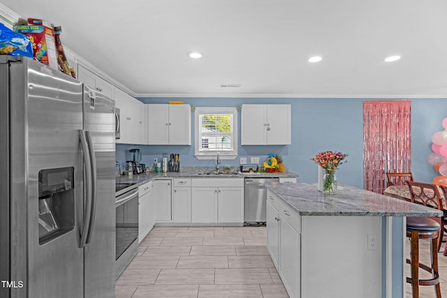 kitchen featuring a kitchen bar, crown molding, appliances with stainless steel finishes, a center island, and a sink