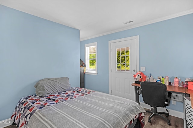 bedroom with crown molding, baseboards, visible vents, and wood finished floors