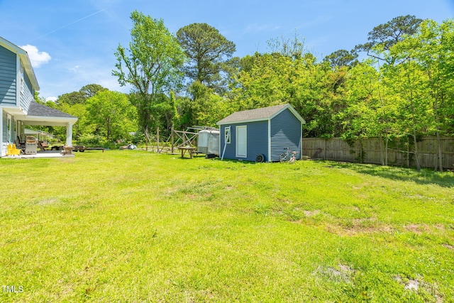view of yard featuring fence, an outdoor structure, and a storage unit