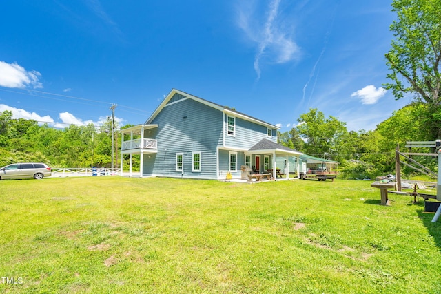 rear view of property featuring fence, a yard, and a balcony
