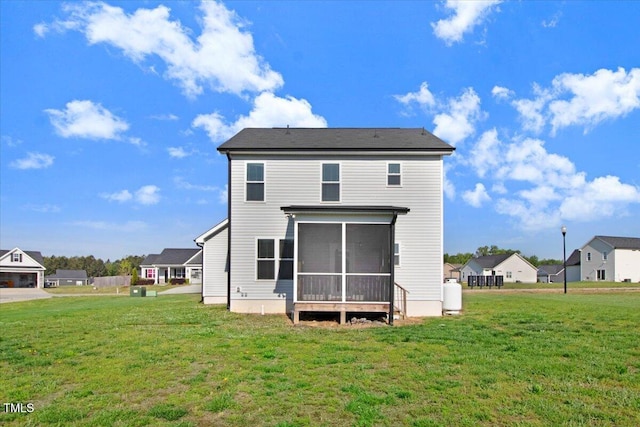 rear view of house featuring a lawn and a sunroom