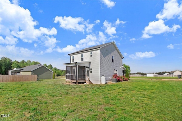rear view of house with fence, a yard, and a sunroom