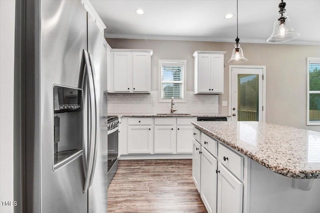 kitchen featuring crown molding, a sink, appliances with stainless steel finishes, and a healthy amount of sunlight