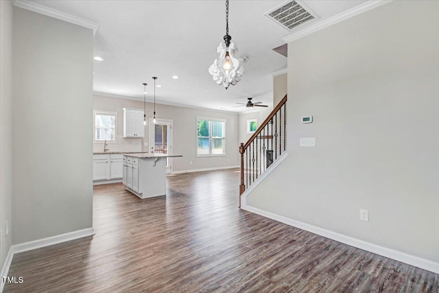 unfurnished living room with ornamental molding, dark wood finished floors, visible vents, and baseboards