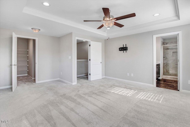 unfurnished bedroom featuring recessed lighting, carpet, a walk in closet, crown molding, and a tray ceiling