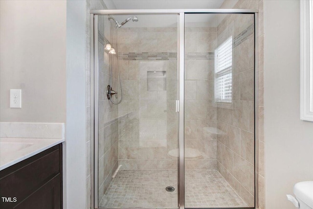 bathroom featuring toilet, vanity, and a stall shower