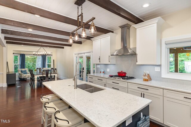 7901 Farnham Ct, Raleigh, NC 27615 - kitchen featuring a sink, wall chimney exhaust hood, a wealth of natural light, and white cabinets