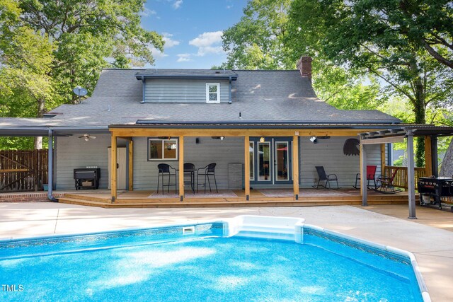 7901 Farnham Ct, Raleigh, NC 27615 - back of house featuring a fenced in pool, roof with shingles, a wooden deck, and a chimney