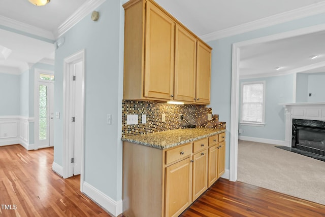 kitchen featuring light brown cabinetry, backsplash, crown molding, and light wood finished floors